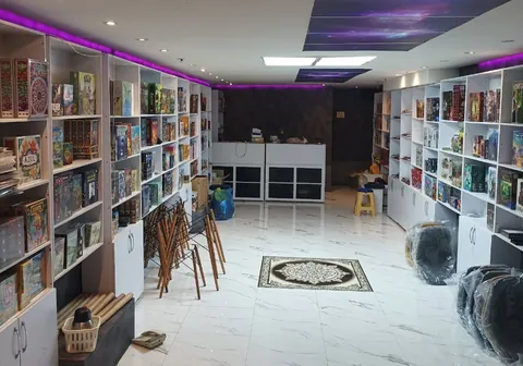فضای داخلی کافهی بازی چترنگ با قفسههای سفید پر از بازی رومیزی